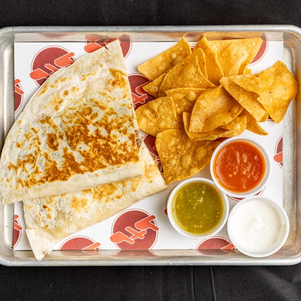 BTB Burrito quesadilla and tortilla chips with salsa verde, red salsa, and sour cream on a tray.