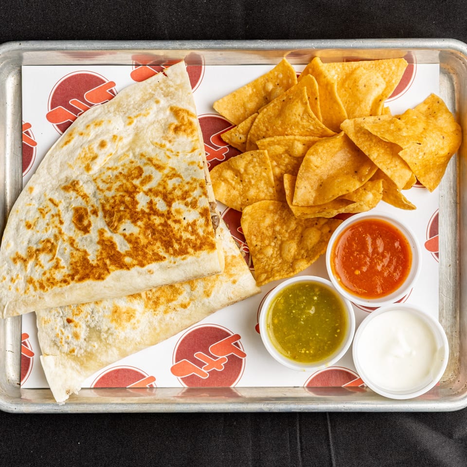 BTB Burrito quesadilla and tortilla chips with salsa verde, red salsa, and sour cream on a tray.
