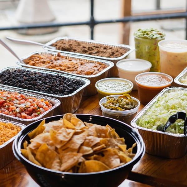 BTB Burrito catering spread with chips, salsa, guacamole, beans, rice, and various toppings in foil containers.
