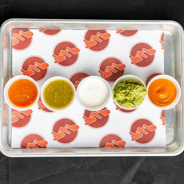 Five small cups of BTB Burrito's Mexican sauces, including salsa, guacamole, and sour cream.