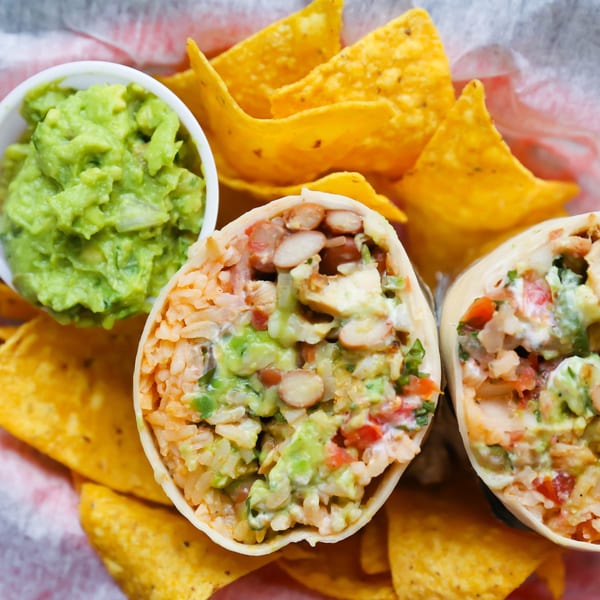 Two BTB Burritos, cut in half, revealing fillings, served with tortilla chips and guacamole.