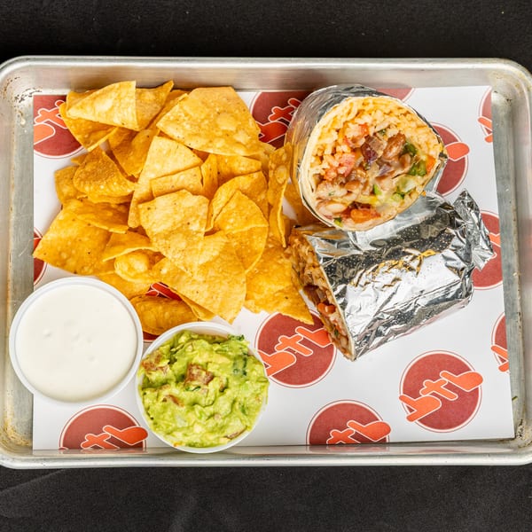 BTB Burrito meal with two foil-wrapped burritos, tortilla chips, guacamole, and sour cream.