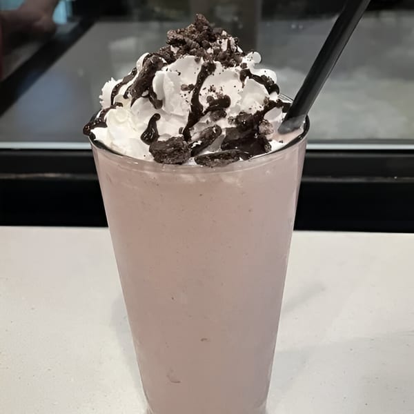 A BTB Burrito milkshake topped with whipped cream, chocolate drizzle, and cookie crumbles.